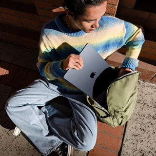 Hình ảnh nhìn từ phía trước của một người đang đặt chiếc MacBook Air 15 inch đã đóng vào trong túi